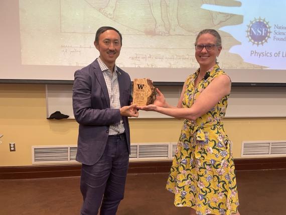 Hu and Keller hold a wooden plaque between them