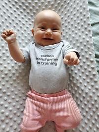 James Gaynor and Katie Corp's baby wearing a shirt that reads "carbon transformer in training"