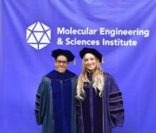 Al Nelson and Gokce Altin wear academic regalia and pose in front of a purple Molecular Engineering & Sciences Institute banner