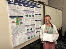 Greta Jacobson poses with a certificate by her award winning poster