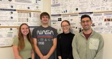 Three students and their mentor near large posters of their research