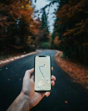 A hand holding a mobile phone with a map