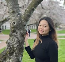 Victoria Pang poses next to a cherry tree on the UW Quad