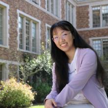 Angela Guo sits outside in the courtyard of a brick academic building