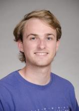 Dylan Rogers wearing a purple t-shirt, smiling for the camera