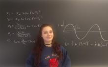 Cecily Rosenbaum stands in front of a blackboard.