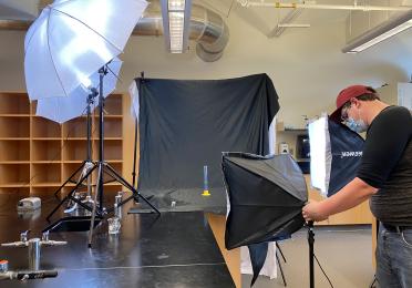 Scientific Instructional Technician Brandon Bol adjusts lighting for a photo shoot in an undergraduate teaching lab to create content for remote instructional material.