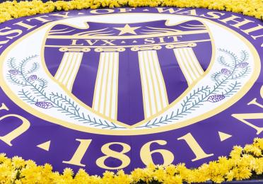 The UW Seal on a large banner surrounded by yellow flowers