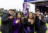 An admitted student and their parents pose with "Dubs Up" with President Ana Mari Cauce.