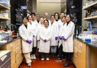 A group of 12 scientists in a chemistry lab