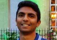 Headshot of Atch Gopalan with short dark brown hair, wearing a blue polo shirt.