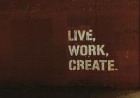 Words stenciled on a brick wall: Live. Work. Create.