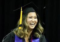 Lucinda Liu wearing a graduation cap and gown standing behind a lectern