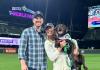 Nick poses with Shannon who holds the chocolate Labrador retriever on the field at T-Mobile Park.