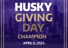Photo of text: Husky Giving Day Champion, April 6, 2023 with a purple background of the Seattle skyline and a gold heart