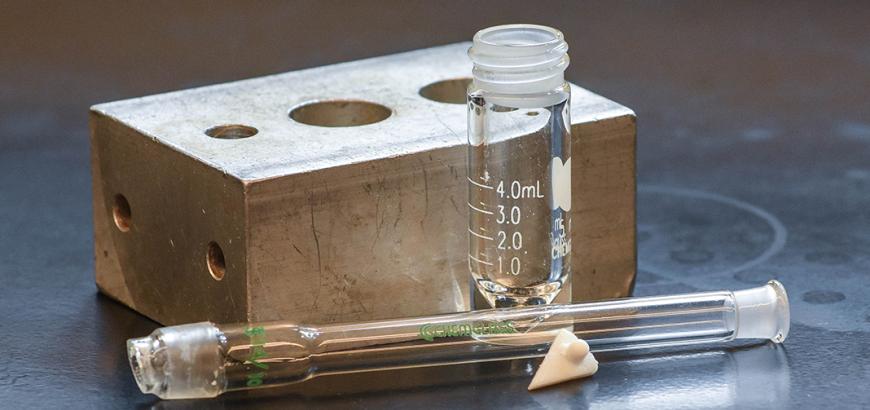 Glassware sits in front of an aluminum block for the Synthesis of Aspirin experiment.