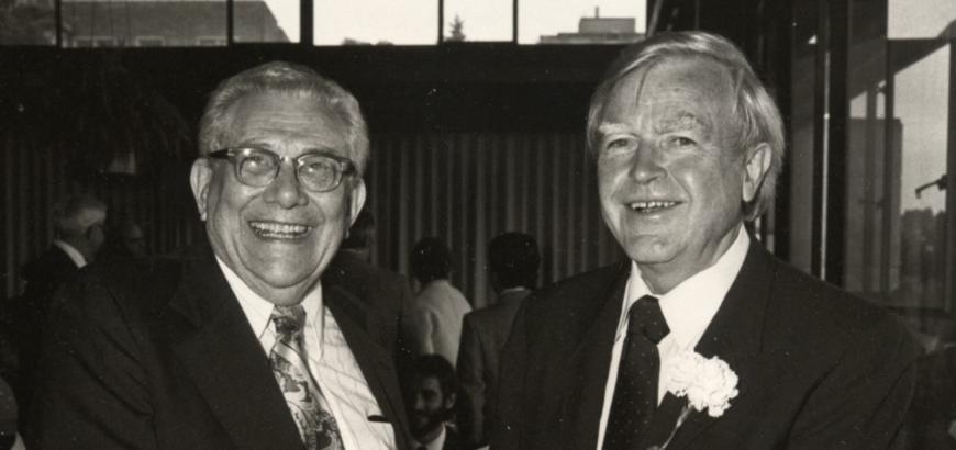 A black and white photo of Lingafelter and Schomaker shaking hands and smiling broadly.