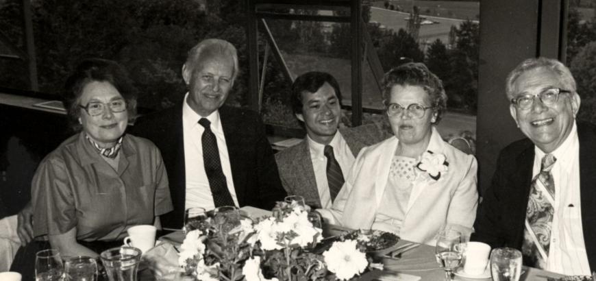 A black and white group photo of two couples sitting at a banquet table with Bernie Santarsiero posed in the middle.