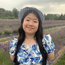 Lily Nguyen wears a dress and sun hat standing in a field of lavender